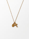 A delicate gold chain necklace featuring a small oval medallion and a dangling cross with three small beads, displayed against a clean white background.